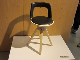 A wooden stool with brown leather cushioning