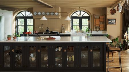 Taupe painted kitchen with large black wooden island with a white stone top, and arched windows