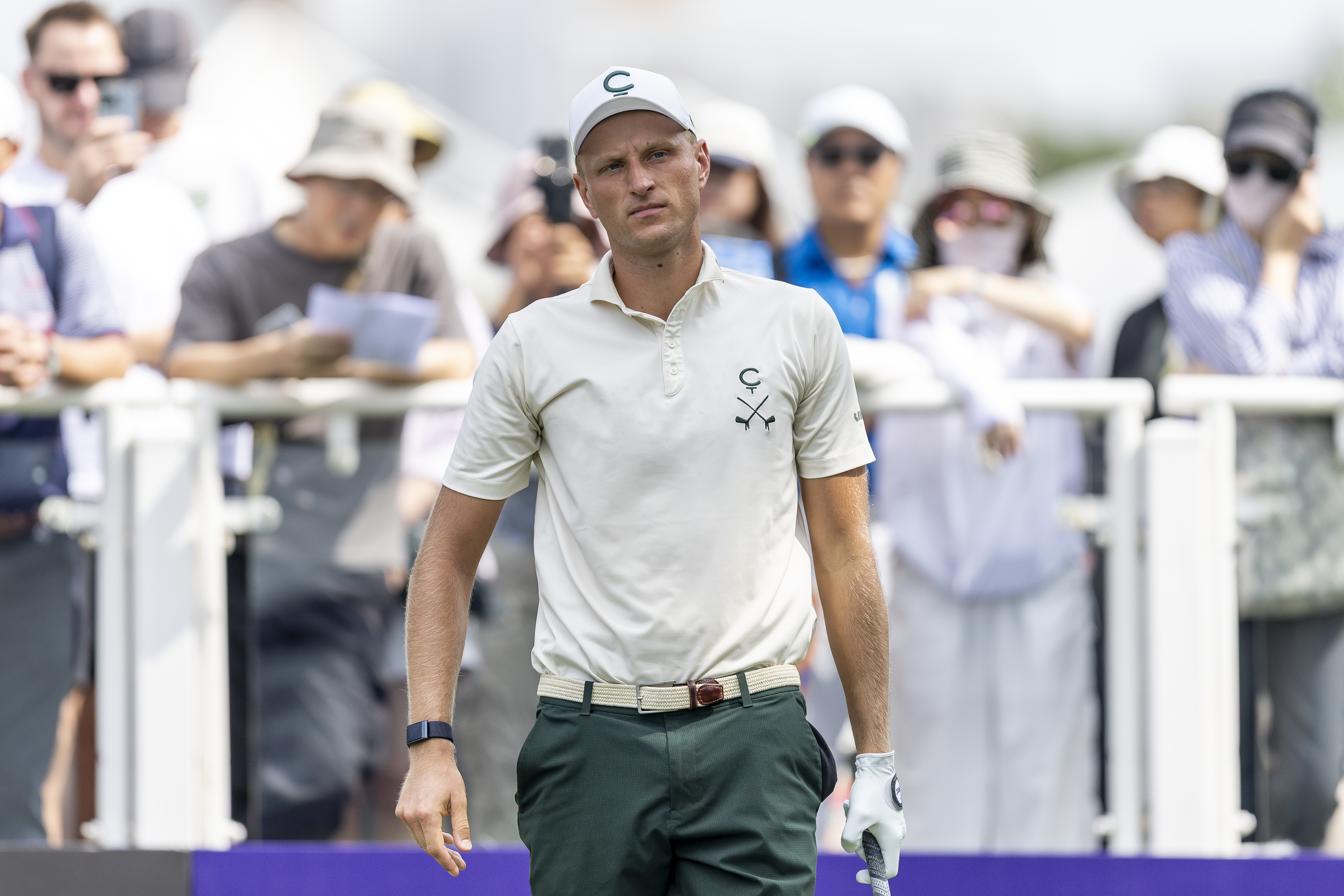 Adrian Meronk walks off the holding a club