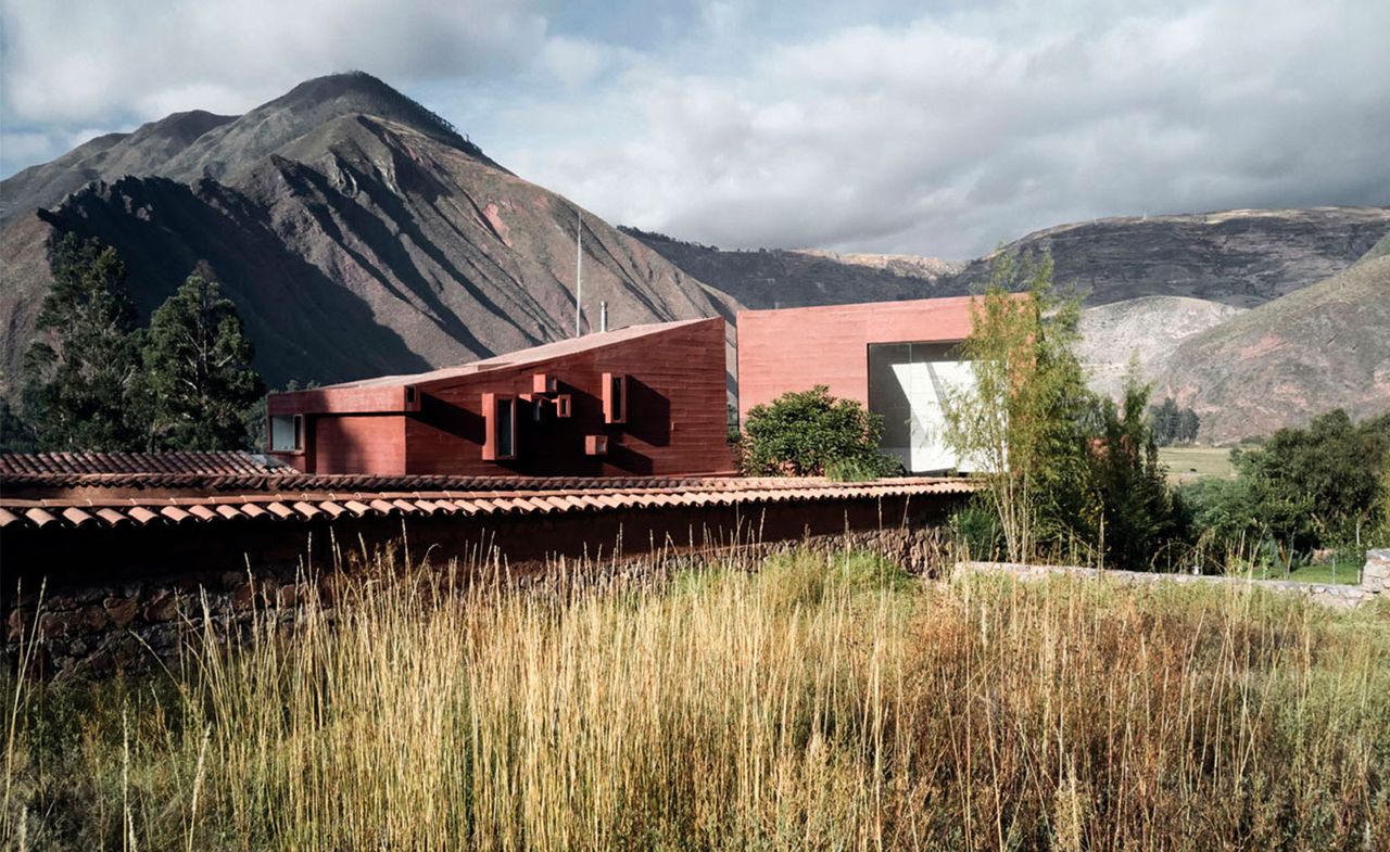 A red coloured house with Peru&#039;s mountains behind designed by Jean-Pierre Crousse