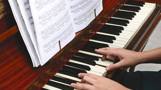 Hands playing an old piano