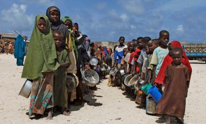 Children from southern Somalia hold their pots as they line up to receive cooked food 