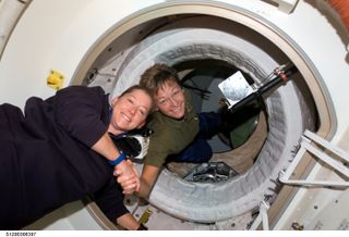Astronaut Peggy Whitson (right), Expedition 16 commander, greets astronaut Pam Melroy, STS-120 commander, after hatch opening between the International Space Station and Space Shuttle Discovery. Whitson is partially in the Pressurized Mating Adapter (PMA-