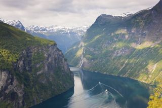 The Geirangerfjord in Norway with snowcapped mountains in the distance