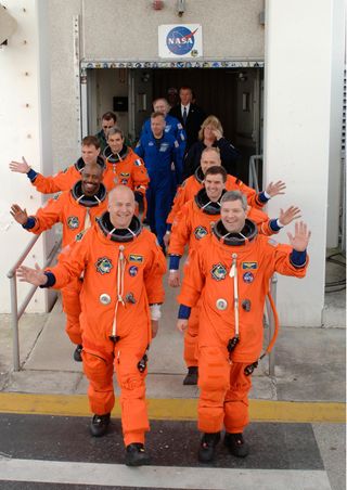 The STS-122 mission crew members stride out of the Operations and Checkout Building at NASA's Kennedy Space Center, eager to ride to the launch pad and take their seats in space shuttle Atlantis for the planned launch at 2:45 p.m. EST. Seen on the right, front to back, are Commander Steve Frick and Mission Specialists Rex Walheim and Hans Schlegel. On the left, front to back, are Pilot Alan Poindexter, followed by Mission Specialists Leland Melvin, Stanley Love and Leopold Eyharts. Schlegel and Eyharts represent the European Space Agency.