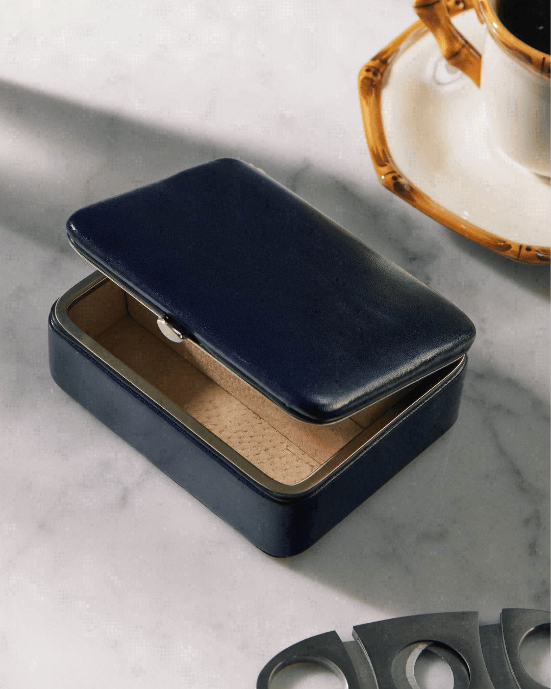Leather Travel Jewelry Box, seen open in a rotating gif shown atop a marble table and against a dark green background.