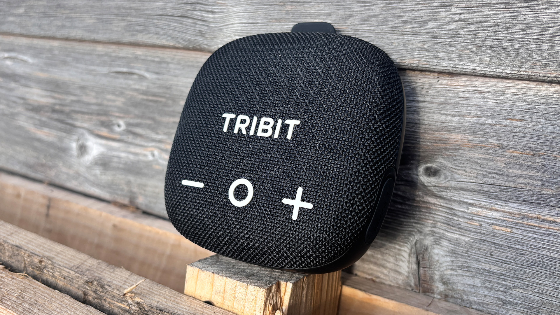 Tribit Stormbox Micro 3 Bluetooth speaker leaning up against wooden fence