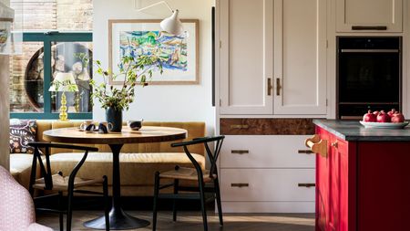 Kitchen diner with eating nook and natural moden accents in the summertime. There are pomegranates in a bowl on the red kitchen island