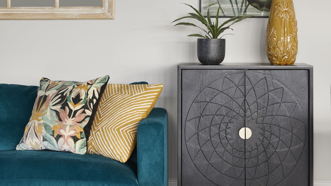 Living room with green velvet sofa, cushions and black cabinet