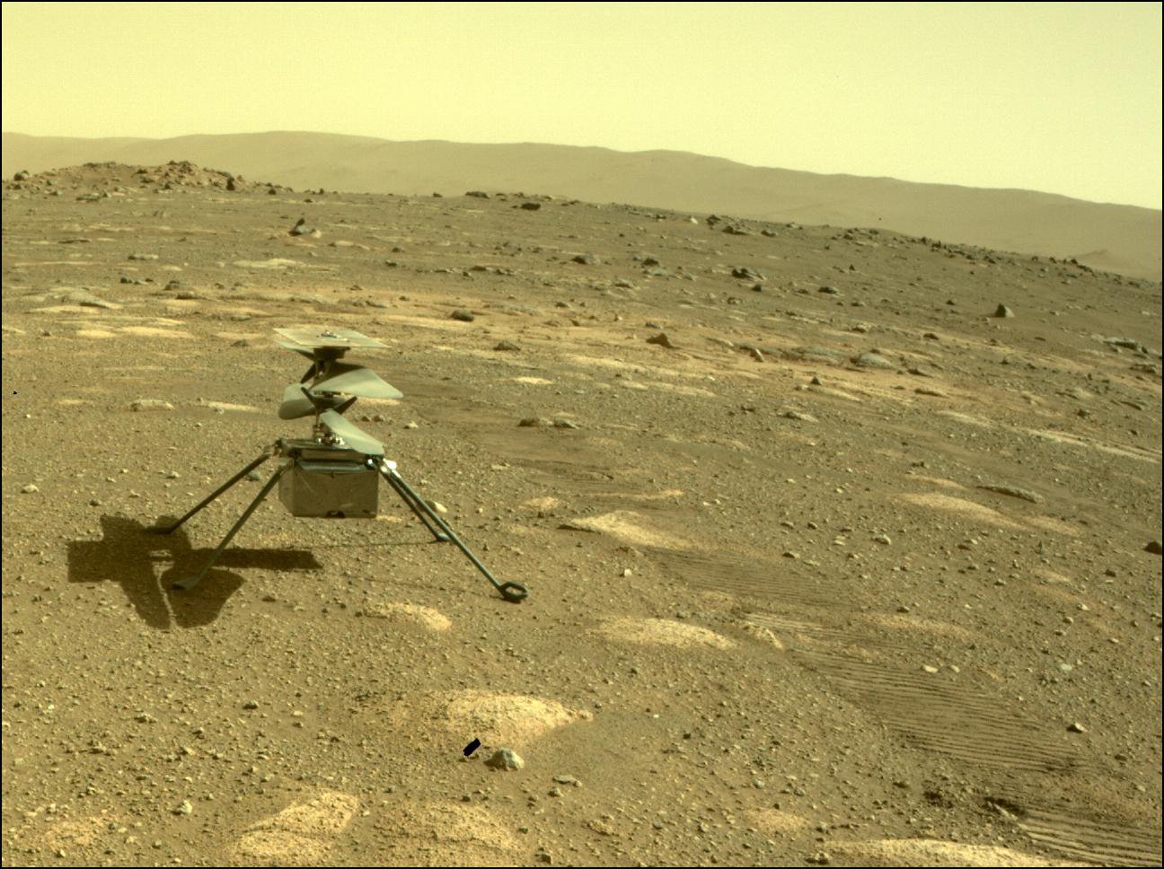 Uma fotografia tirada pelo rover Perseverance do helicóptero Ingenuity na superfície de Marte em abril, logo após o rover lançar o helicóptero.