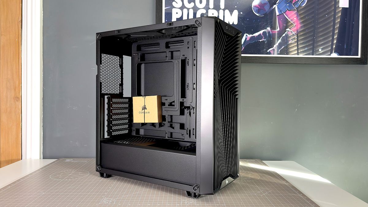 A Corsair PC case, the 3200D, on a desk with various panels removed and ready for a PC build.