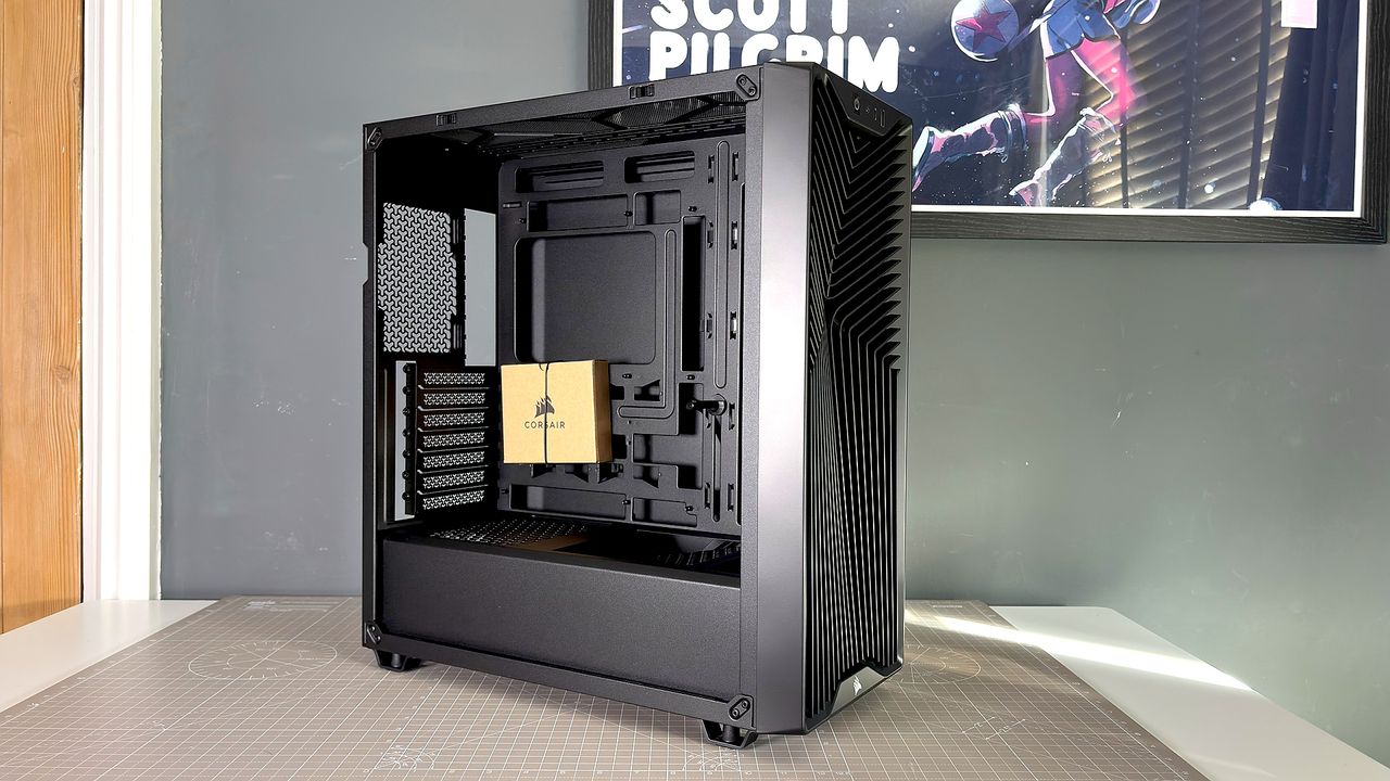 A Corsair PC case, the 3200D, on a desk with various panels removed and ready for a PC build.