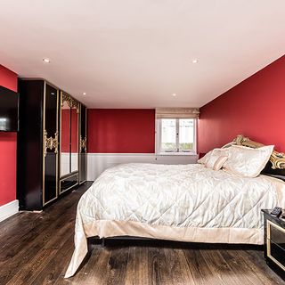 red bedroom with wooden flooring and black wardrobe