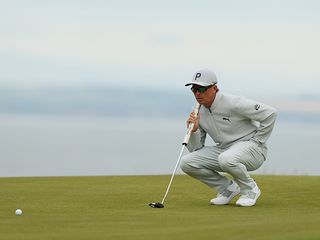 Rickie Fowler reading the line of a putt on the green