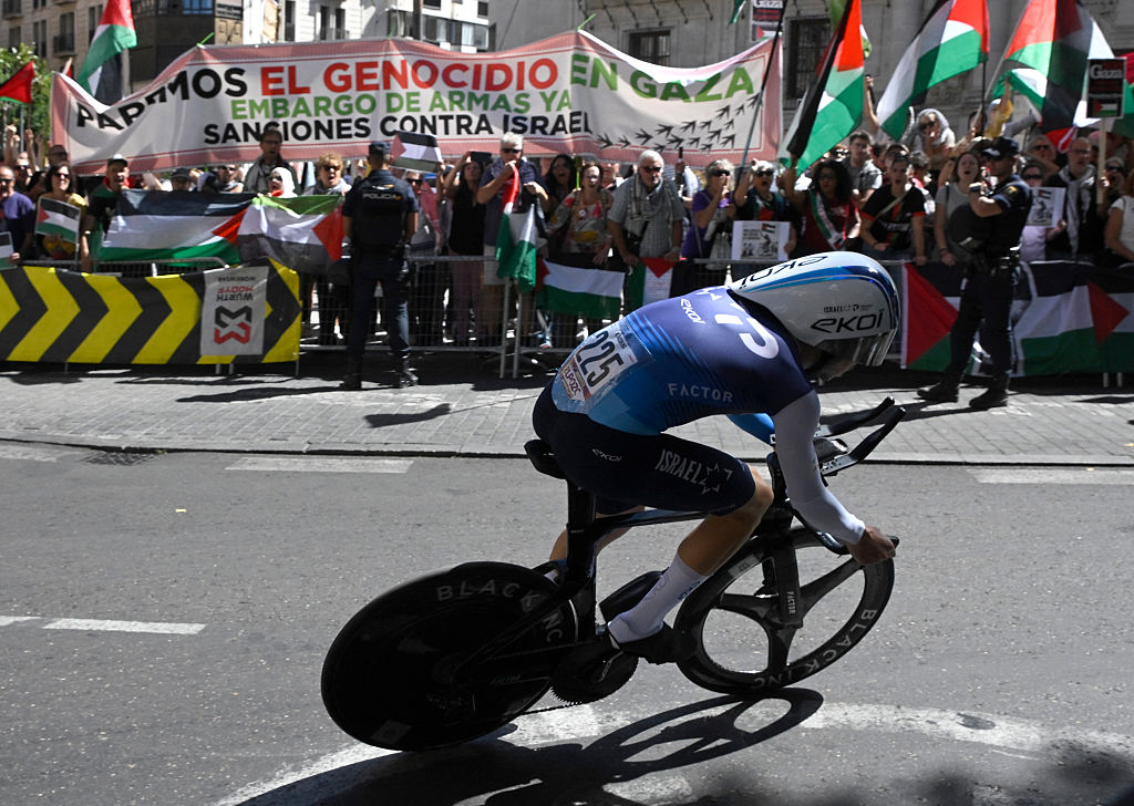 Pro-Palestinians protesters wave Palestinian flags as Team Israel Premier Tech&#039;s Israeli rider Nadav Raisberg competes during the 18th stage of the Vuelta a Espana, a 26 km race against the clock between Valladolid and Valladolid, on September 11, 2025. (Photo by Miguel RIOPA / AFP)