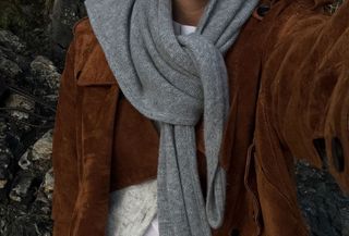 Woman wearing a brown suede jacket and a gray scarf.