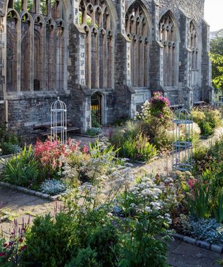 A church ruin surrounded by a stone path and flower beds.