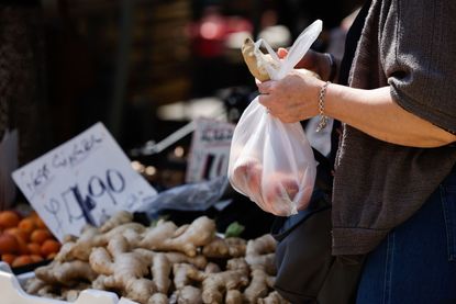 A trader wraps up a vegetable for a customer (image: Photographer: Jason Alden/Bloomberg via Getty Images)