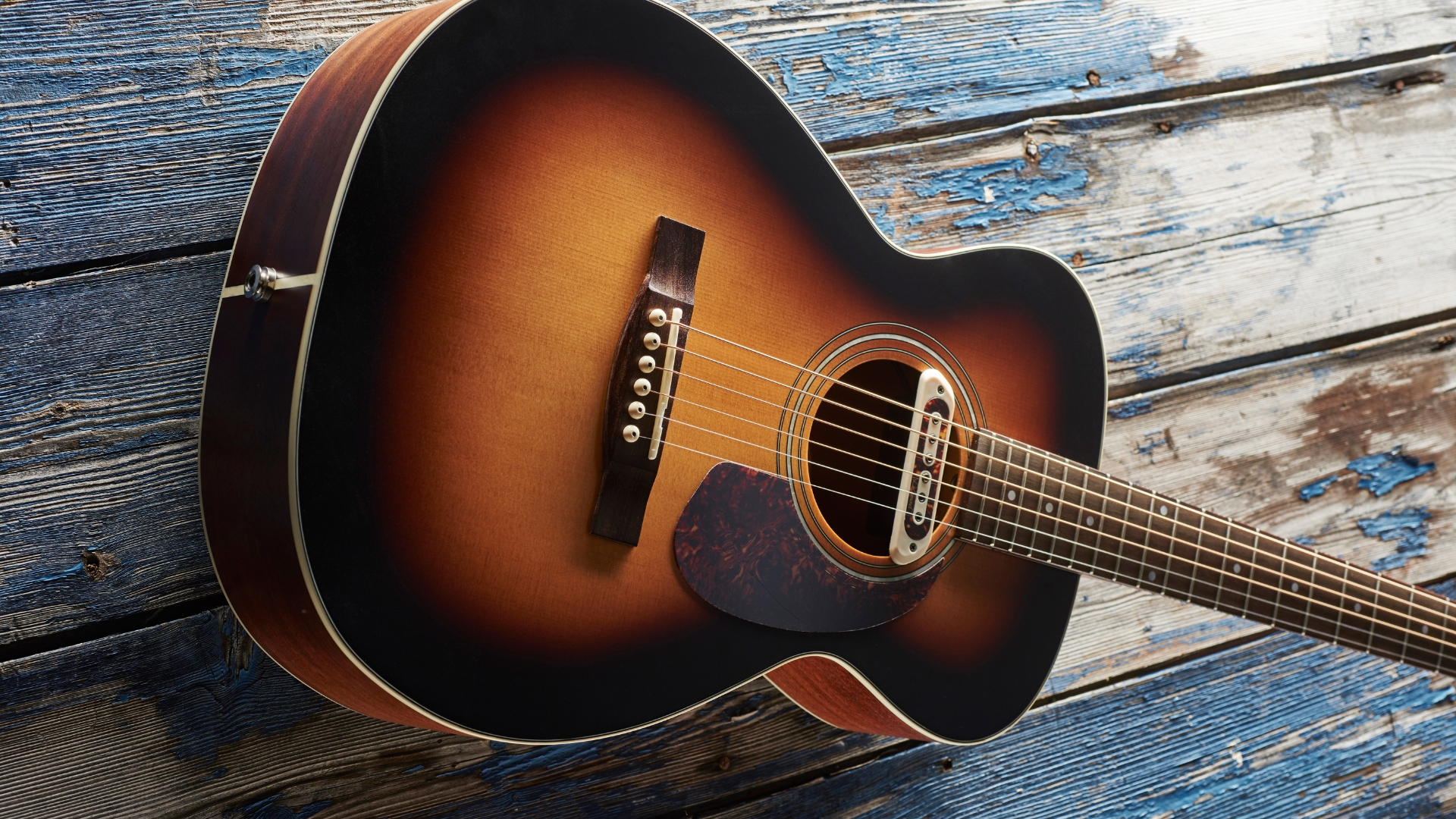 A Guild M-240E Troubador acoustic guitar on a wooden floor