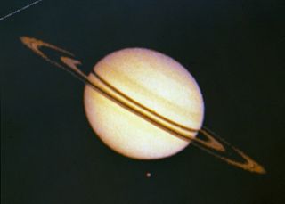 Saturn and its moon Titan as seen by Pioneer 11 in 1979. The irregularities in ring silhouette and shadow are due to technical anomalies in the preliminary data later corrected. At the time this image was taken Pioneer 11 was, at that time, 2,846,000 km (1,768,422 miles) from Saturn.