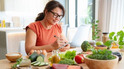 middle-aged woman makes notes of healthy foods