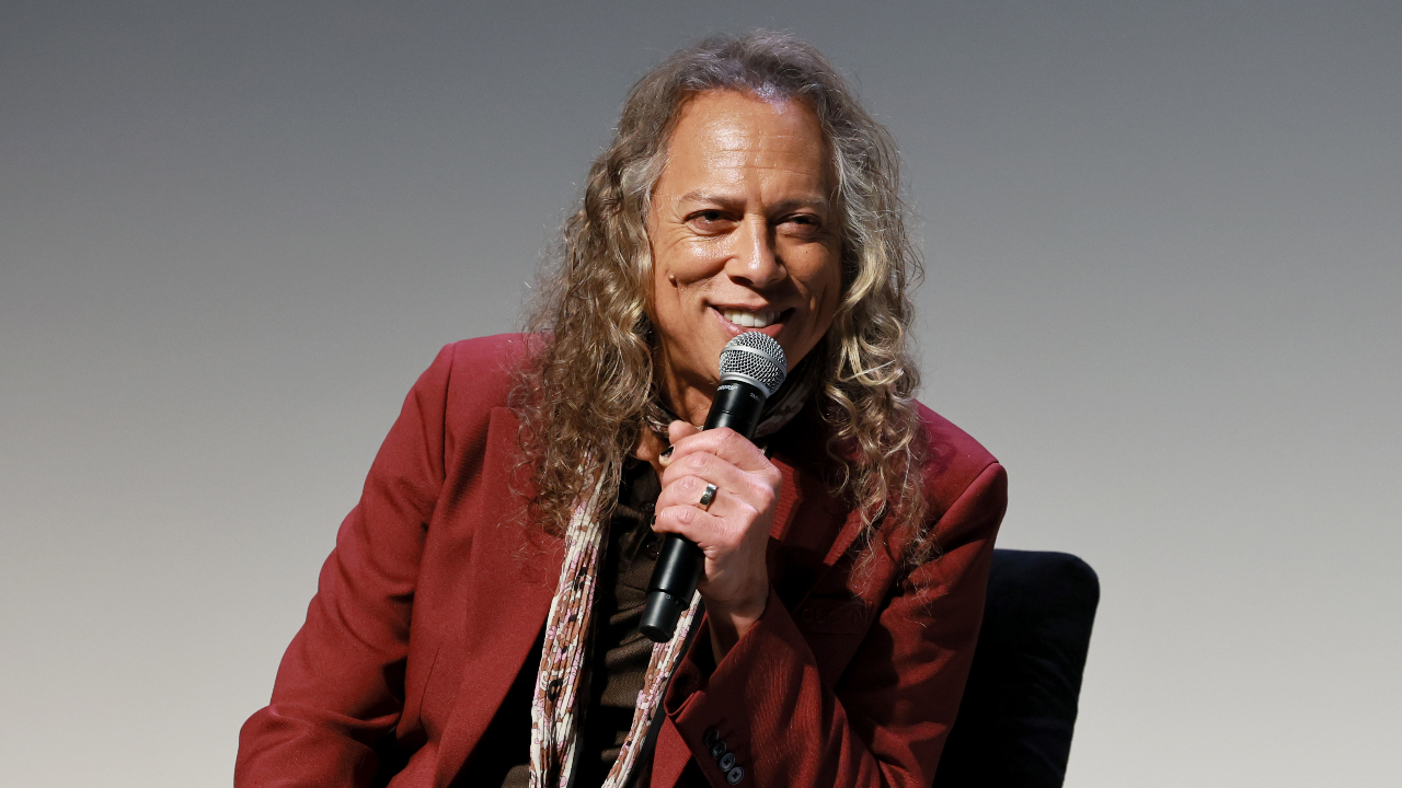 Kirk Hammett smiling and holding a microphone