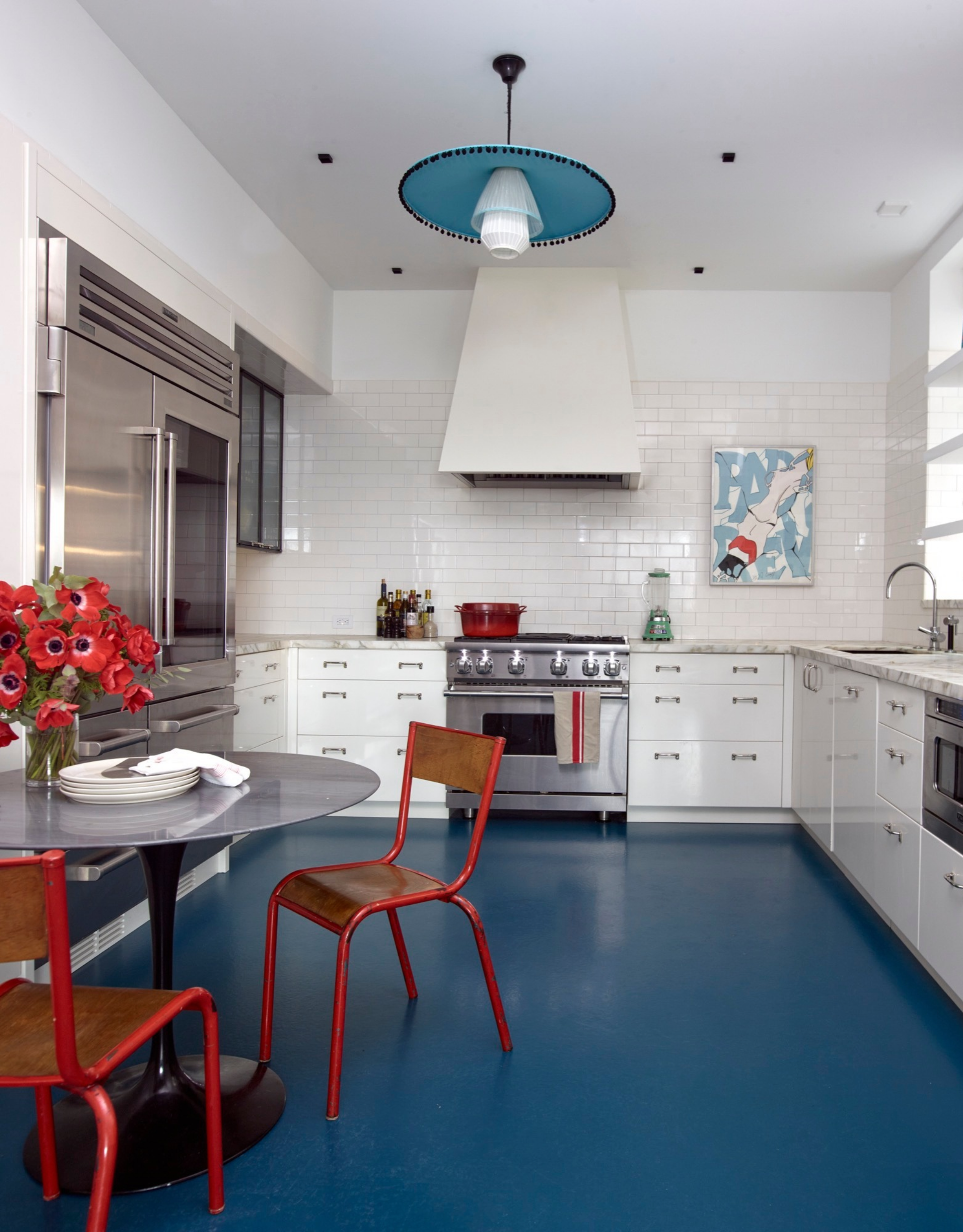 small kitchen with blue floors, white cabinets, red chairs and steel appliances