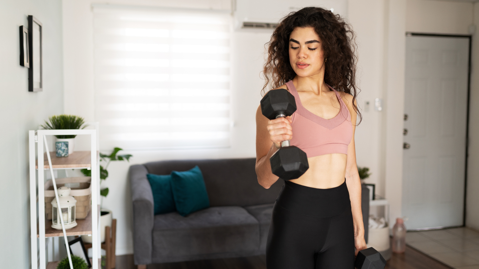 A woman performs an alternating hammer curl with dumbbells