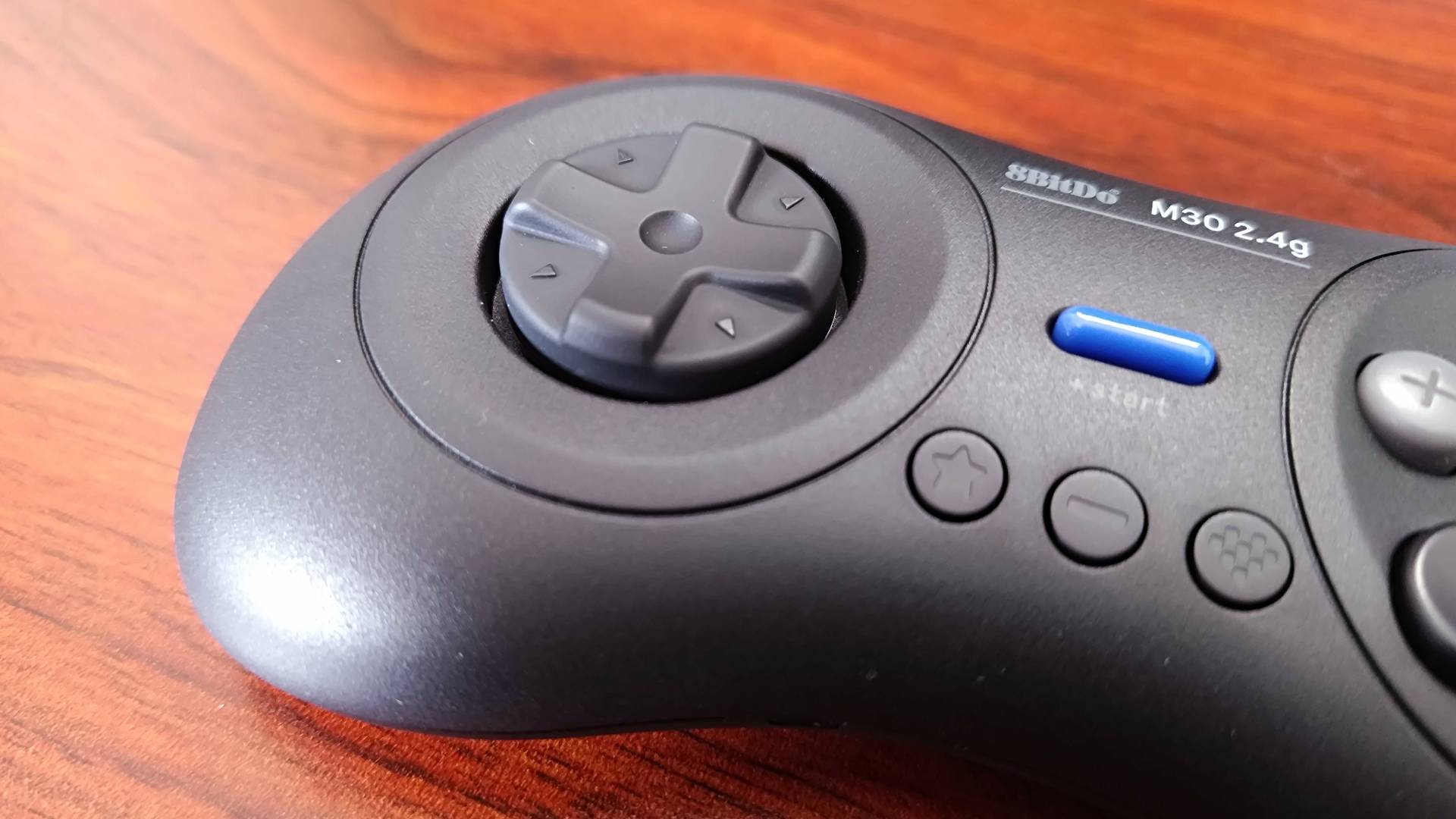 Close up of 8Bitdo M30 d-pad on woodgrain desk.