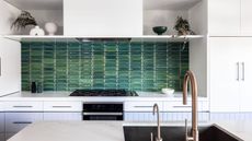 A tiled green splashback with white upper cabinets and lavender lower cabinets. 