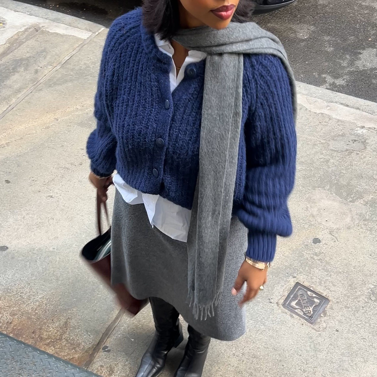 a woman wearing a blue sweater and gray skirt