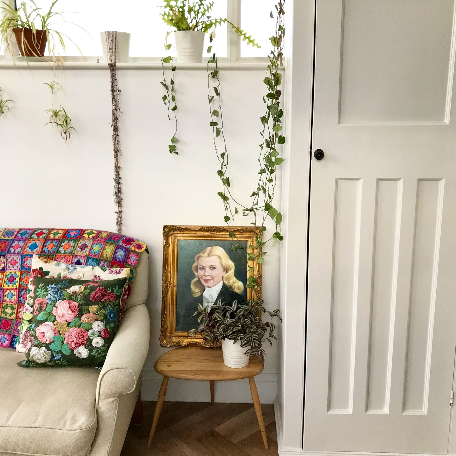 white sofa with vintage cushions and a vintage painting propped on an end table