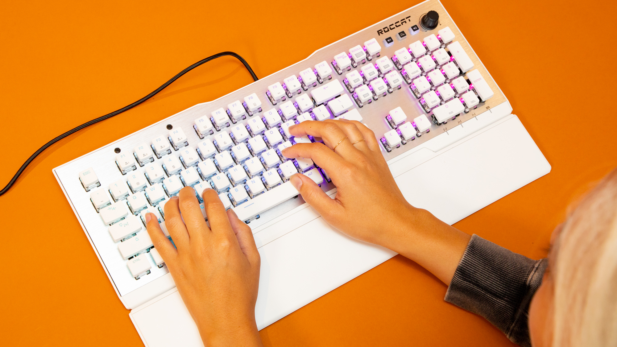 Roccat Vulcan 122 Aimo in white on an orange desk with someone using it