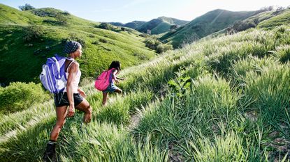 A woman and young girl feeling the incline walking benefits whilst hiking up a hillside