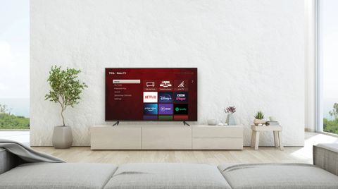 The TCL 55RP620K 4K TV sat on a TV unit next to houseplants and in front of a grey sofa