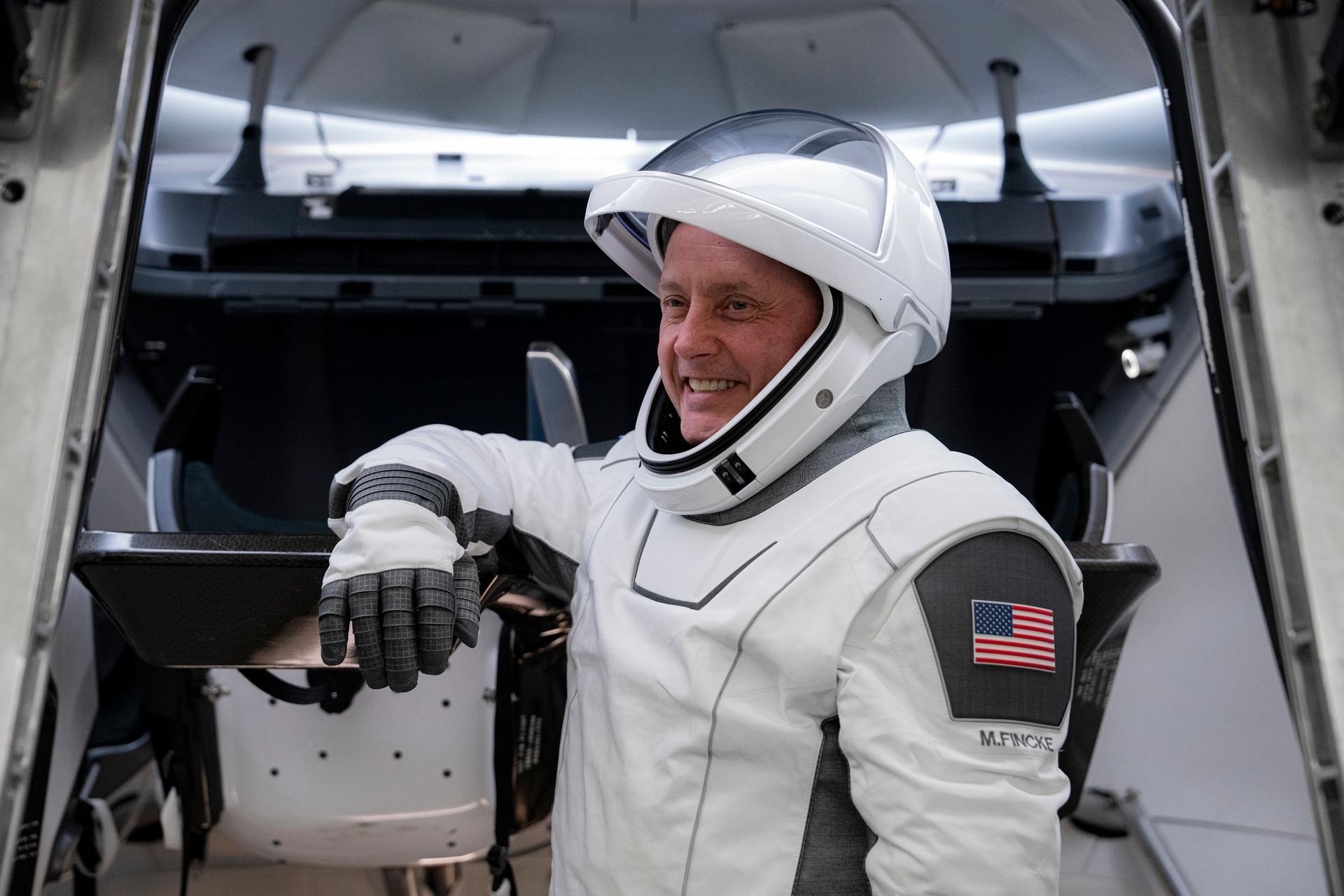 astronauts in white spacesuits pose for portraits