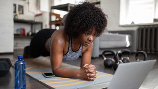 How to get a stronger core: Image shows woman performing plank position in front of laptop