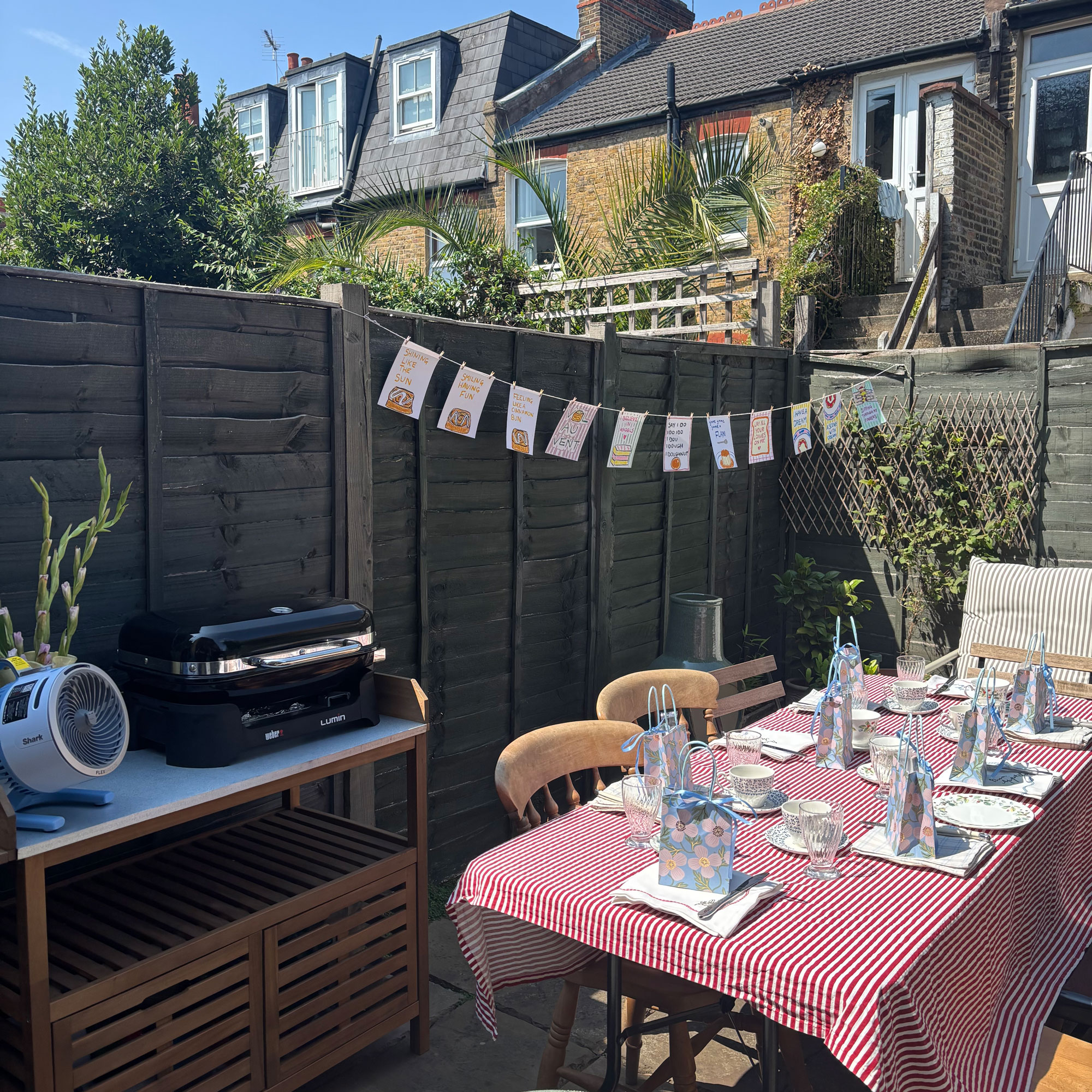 Small garden with green fence, small potting bench and table with red table cloth