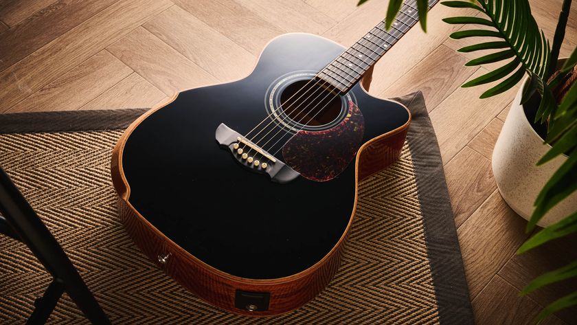 Harley Benton CLC-650SM-CE: the affordable cutaway electro-acoustic has a black top, natural back and sides, with an attractive arm-rest and tortoiseshell pickguard, and is here photographed against a wooden floor.