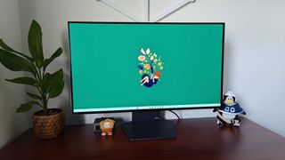 LG UltraGear 32GS95UE-B on woodgrain desk with Windows 11 and green Kiki's Delivery Service wallpaper on screen