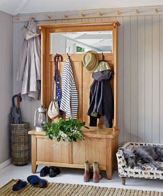 An example of mudroom storage ideas showing a mudroom with all-in-one wooden storage unit and a dog sleeping in a cream dog bed