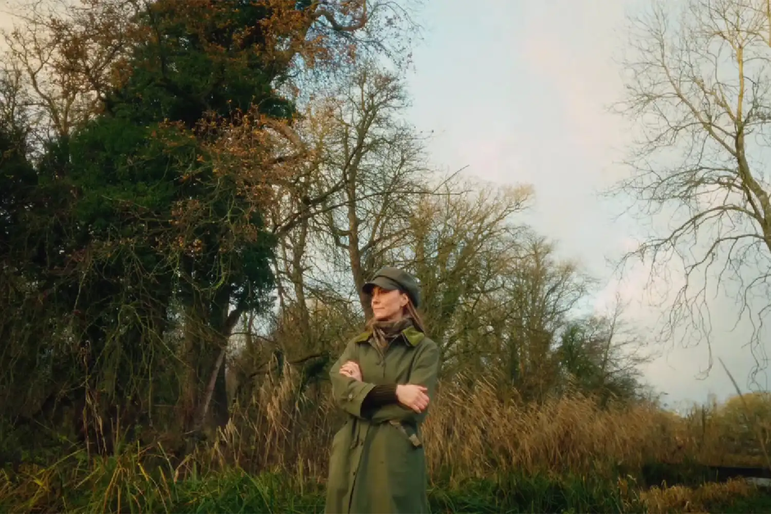 Princess Kate wearing a green coat folding her arms in the woods