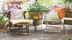 A garden in summer with two deckchairs with cushions on decking to support a guide on how to clean decking