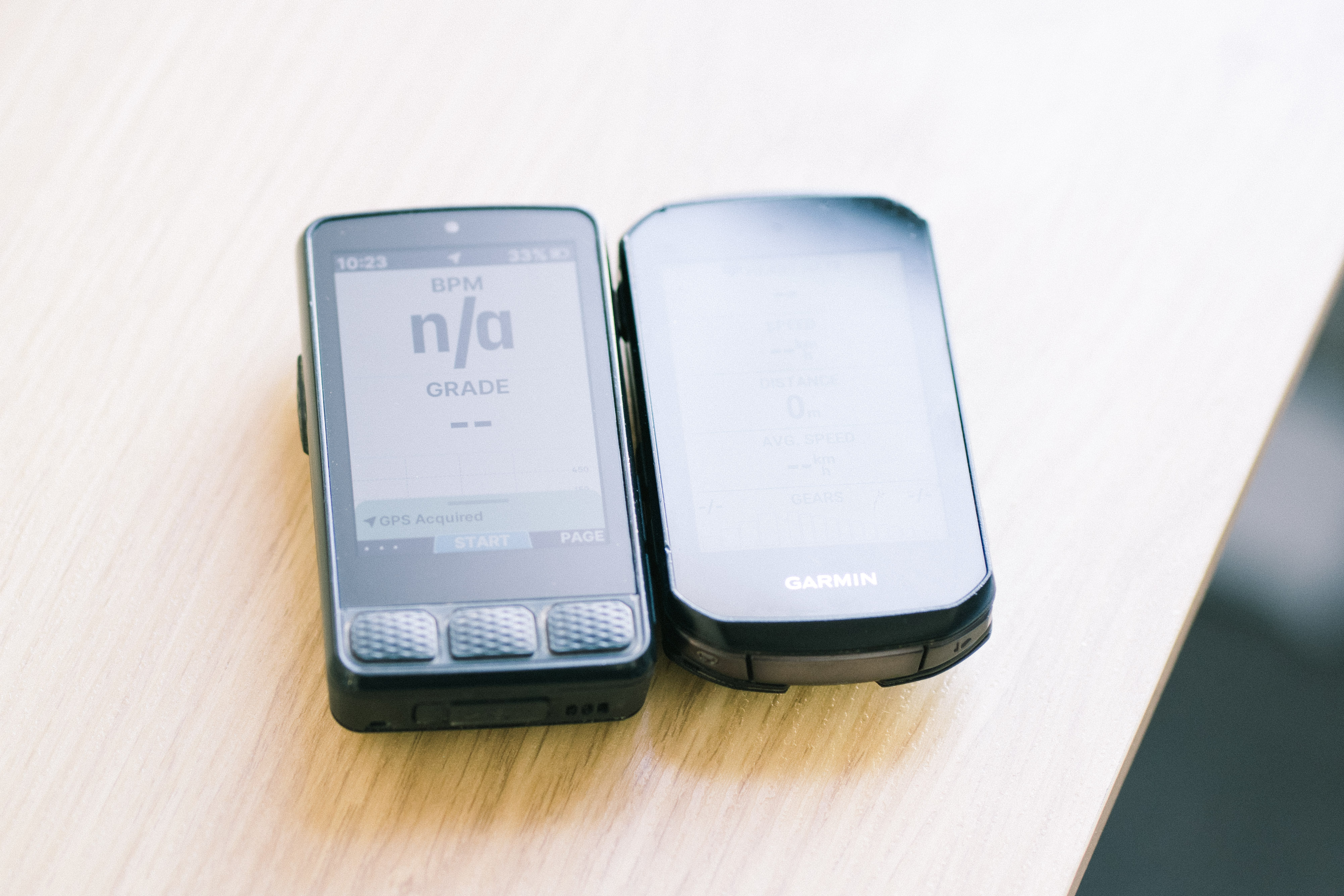 Two bike computers side by side, one with a matte screen, one with a shiny one