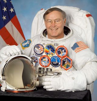 Astronaut Jerry Ross poses for a NASA official portrait wearing the mission patches from his record seven spaceflights.