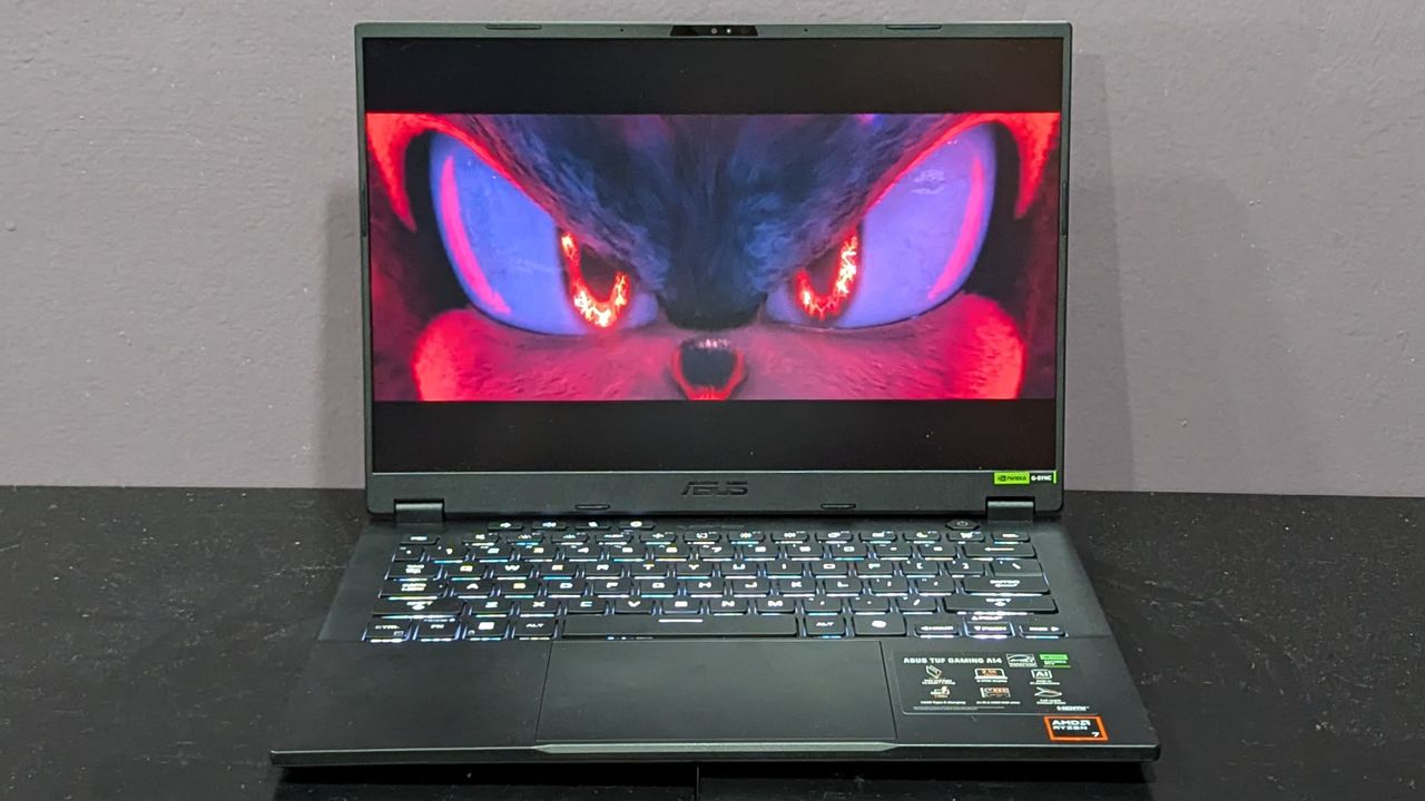 The Asus TUF Gaming A14 streaming a video, on a black desk against a gray wall.