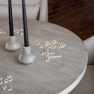 Two marble candle holders on a table with scrabble tiles