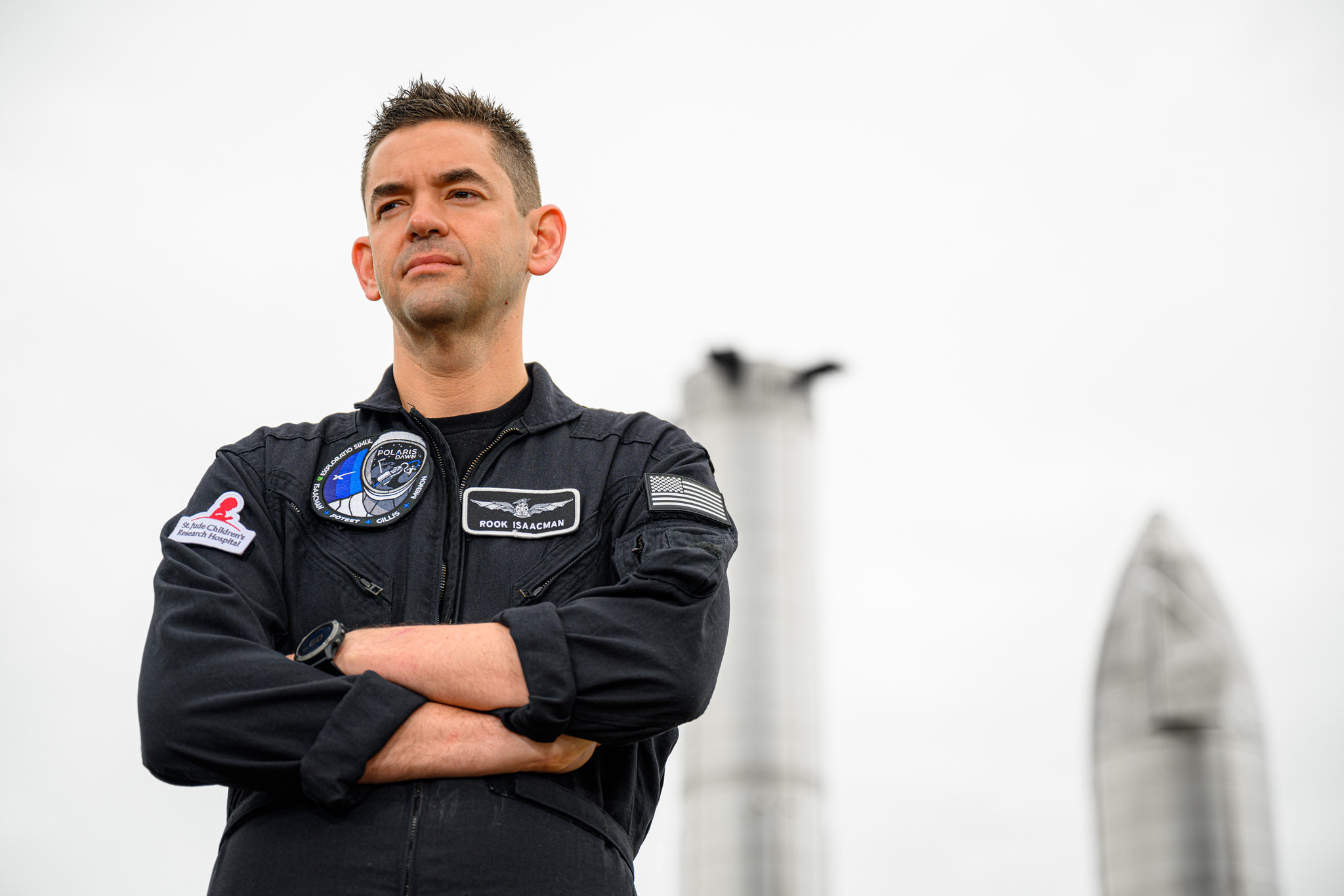 Jared Isaacman pose devant des maquettes de vaisseaux spatiaux