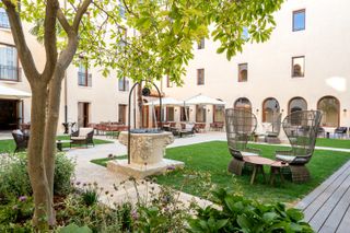 The main courtyard at Ca’ di Dio hotel in Venice, with green lawns, pathways and outdoor furniture