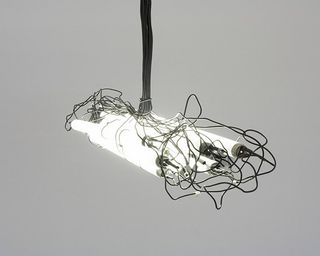 A bundle of white light tubes held together and suspended by messy black wiring